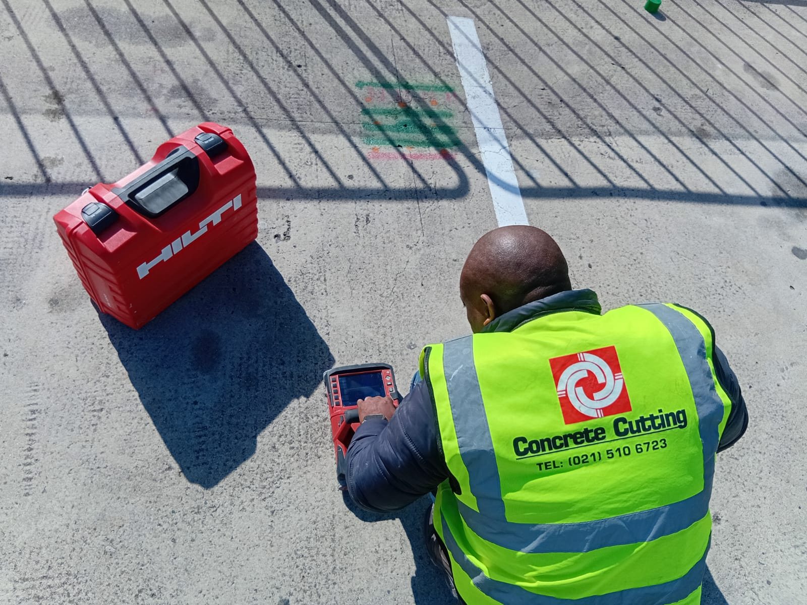CCS technician reviewing a Hilti concrete scan beside marked positions on a slab