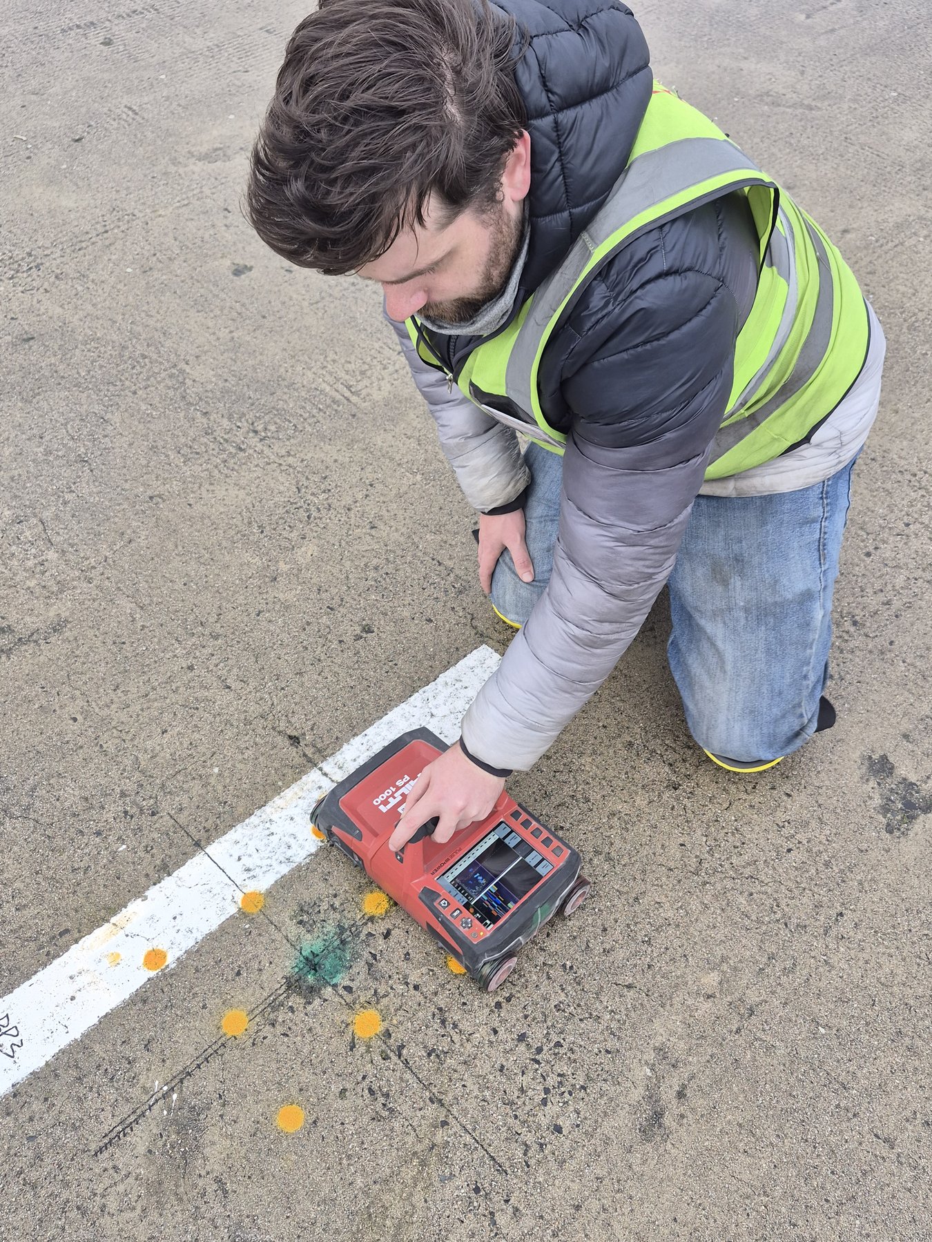 CCS technician operating a Hilti PS 1000 concrete scanner over marked positions on a slab