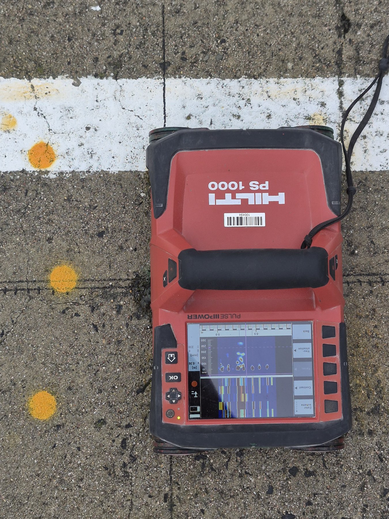 Close-up of a Hilti PS 1000 scanner displaying concrete scan results beside marked slab positions